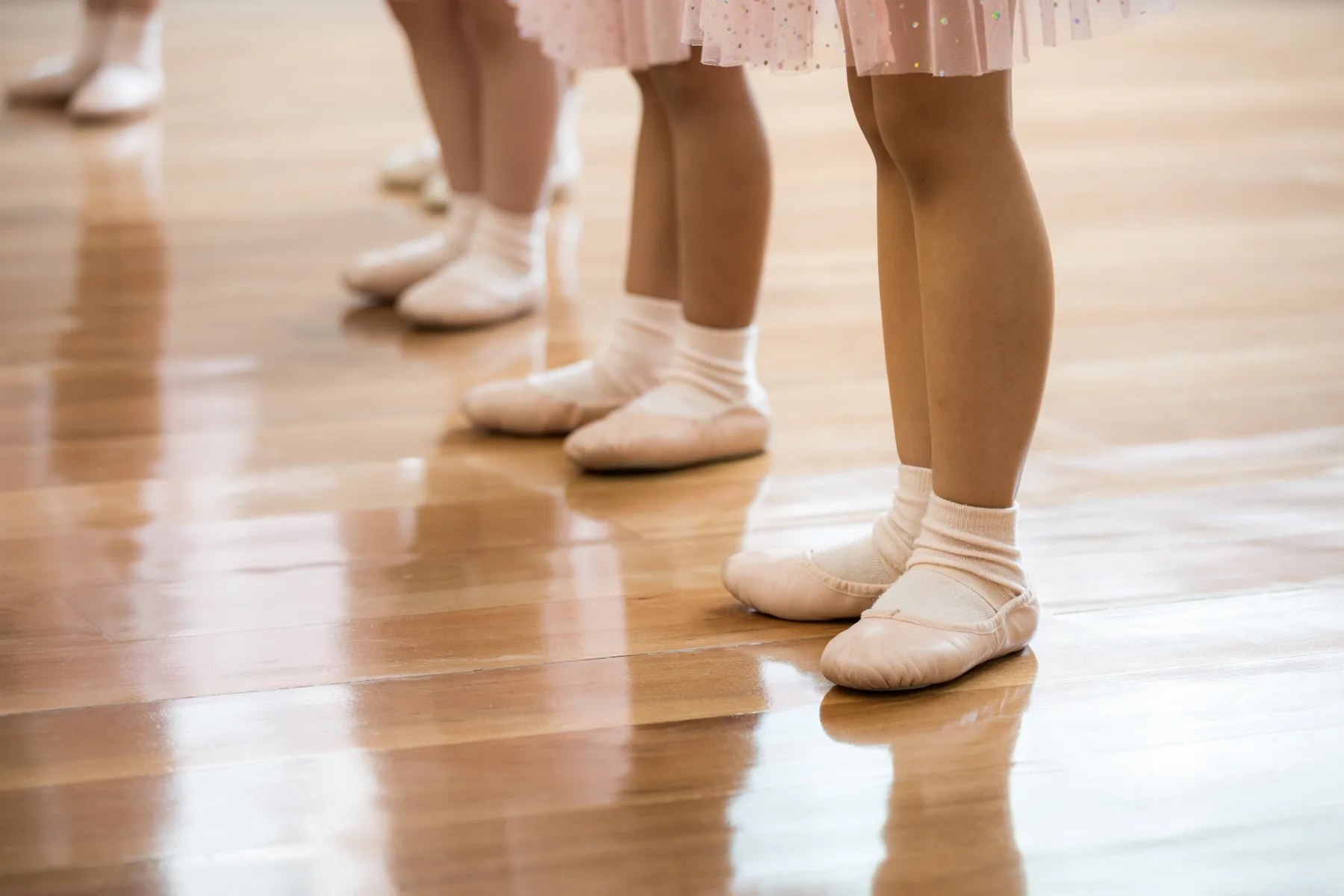 Children's feet in ballet slippers on a wooden studio floor