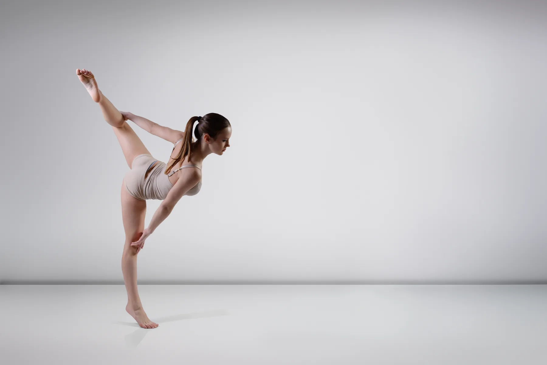 A dancer extending mid-movement in a bright, empty studio
